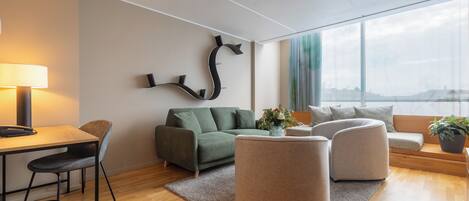 Un salon moderne avec un canapé vert, deux fauteuils, une table basse et une lampe.