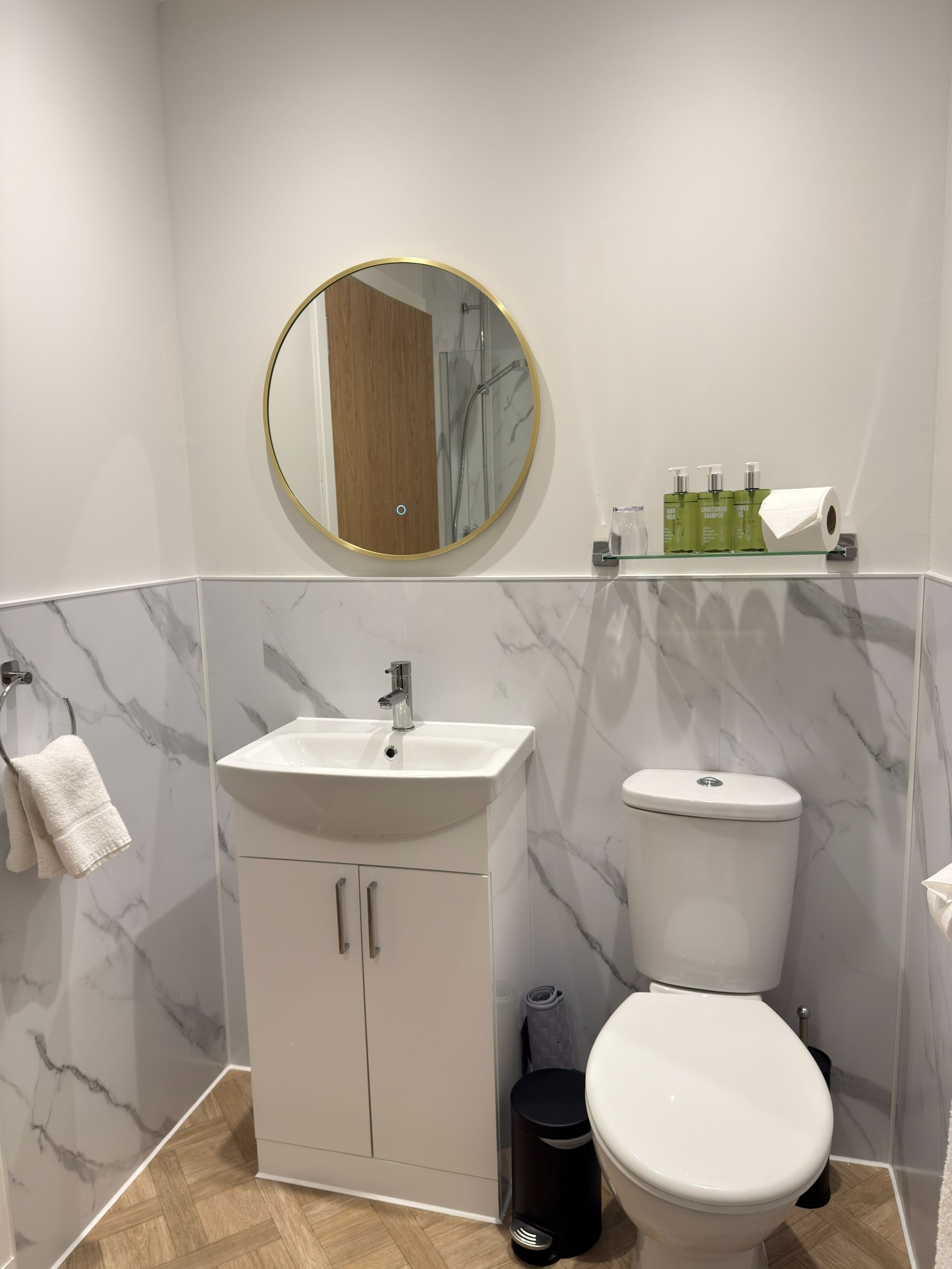 Ein Badezimmer mit einem weißen Waschbecken, einer Toilette und einem Spiegel mit goldener Rahmung.