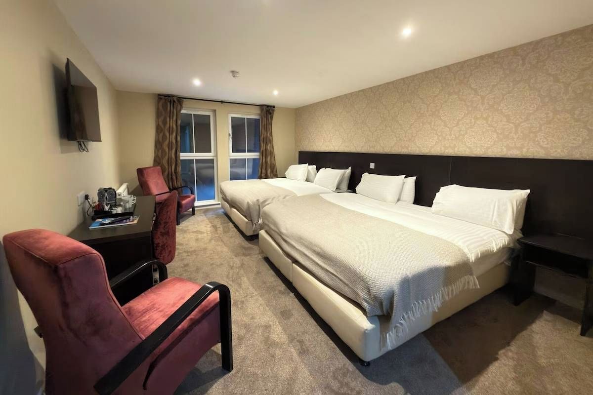 Une chambre d’hôtel avec un grand lit, un bureau, une chaise et un téléviseur.