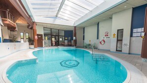An indoor swimming pool with a clear ceiling, lounge chairs, and safety signs. - Craigmonie Hotel Inverness by Compass Hospitality (Inverness)