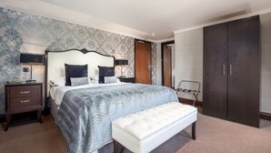 A bedroom with a large bed, a bench, a wardrobe, and a nightstand with a lamp. - Craigmonie Hotel Inverness by Compass Hospitality (Inverness)