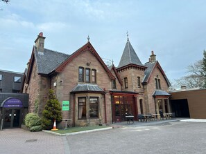 A historic building with a reception area, outdoor seating, and a stone facade. - Belvilla Inverness Craigmonie Hotel (Inverness)