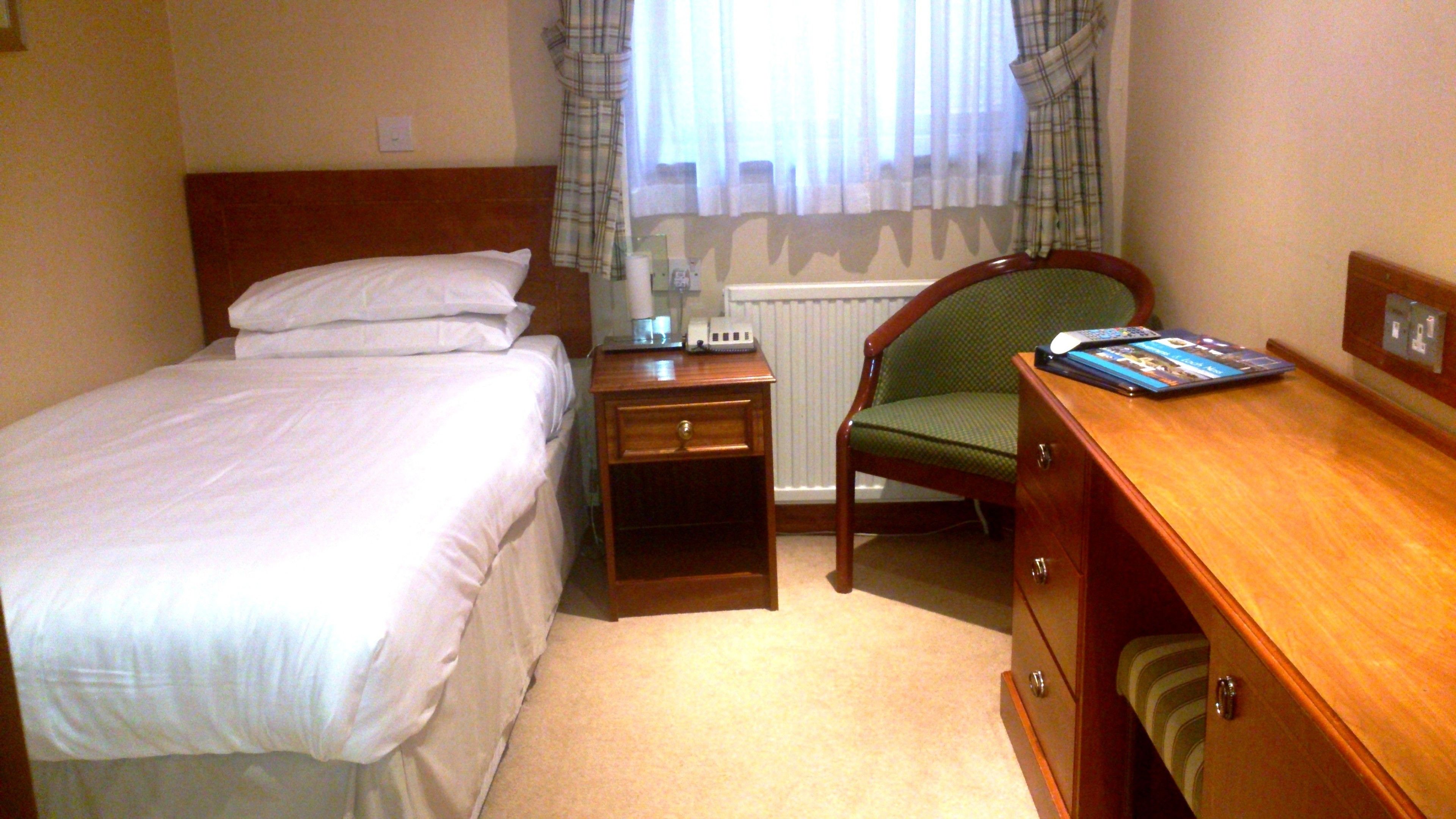 Ein Hotelzimmer mit Bett, Nachttisch, Stuhl und Schreibtisch.