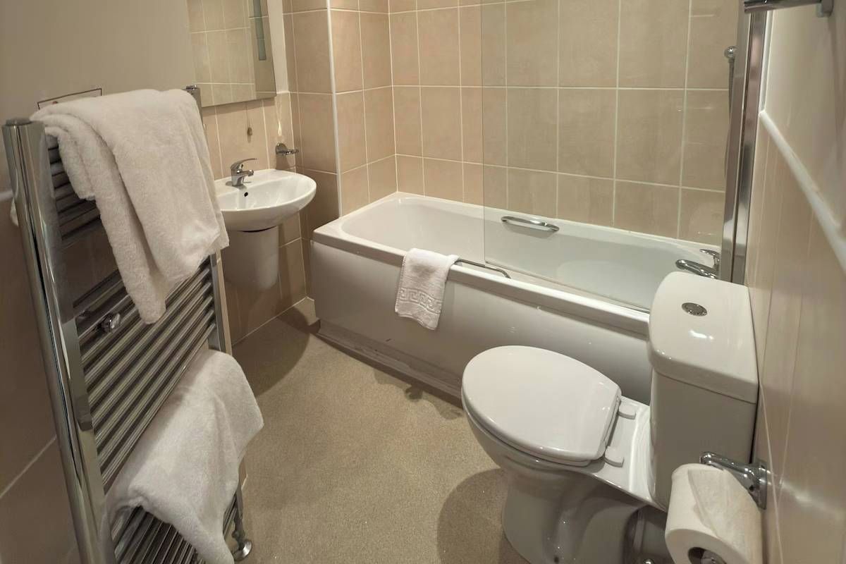 A bathroom with a bathtub, toilet, sink, and towel rack.