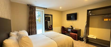 A hotel room with a bed, a desk, a chair, a television, and a wardrobe.