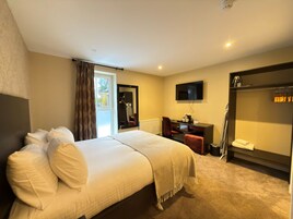 Una habitación de hotel con cama, escritorio, silla, televisor y armario.