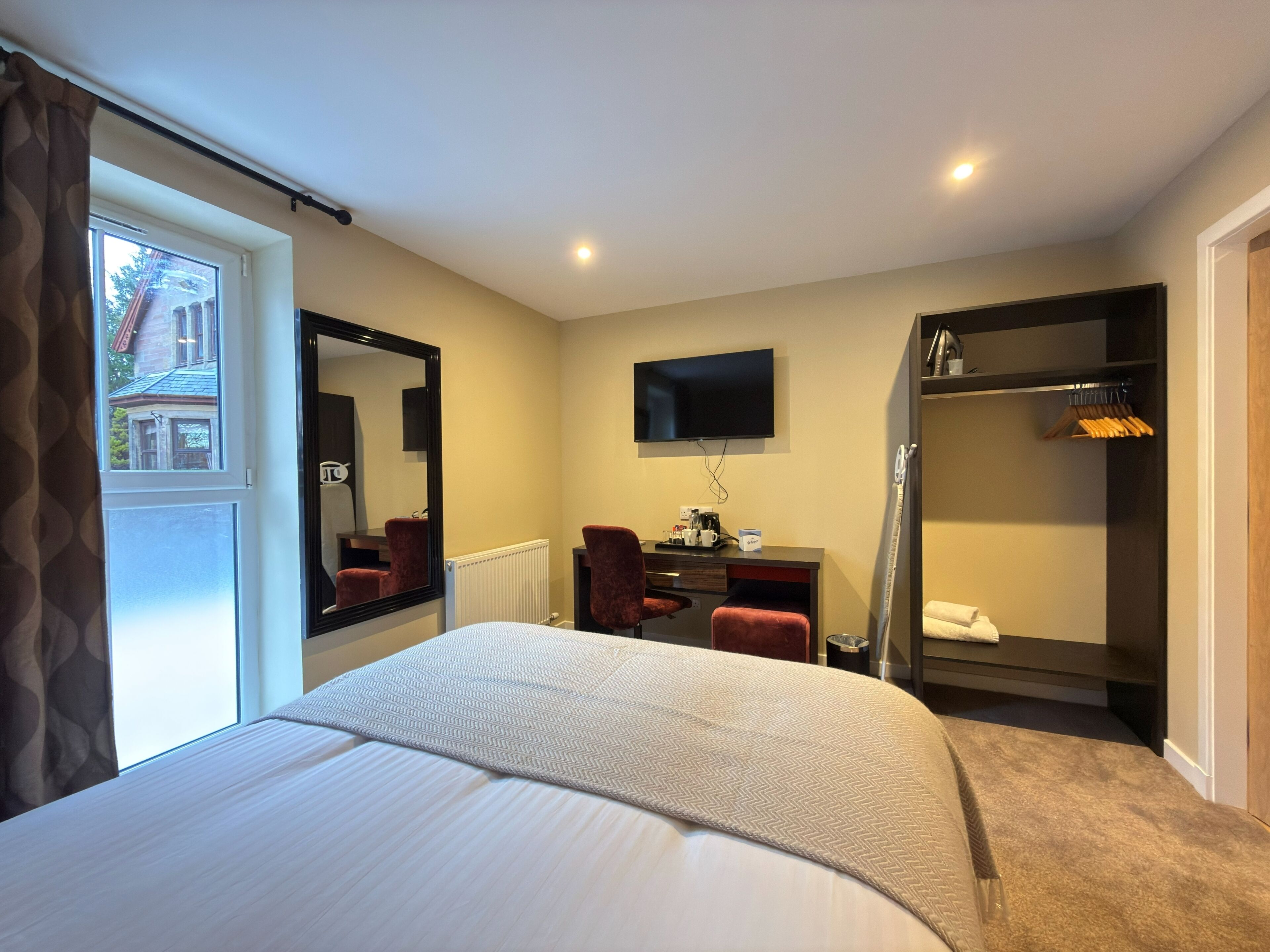 Habitación de hotel con cama, escritorio, silla, televisión y armario.
