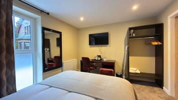 Habitación de hotel con cama, escritorio, silla, televisión y armario.