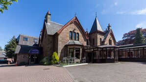 A historic building with a reception area, outdoor seating, and a covered walkway. - Craigmonie Hotel Inverness by Compass Hospitality (Inverness)