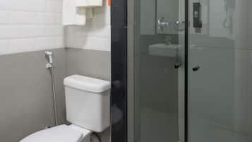 Un bany modern amb vàter, una dutxera de vidre i un lavabo blanc.