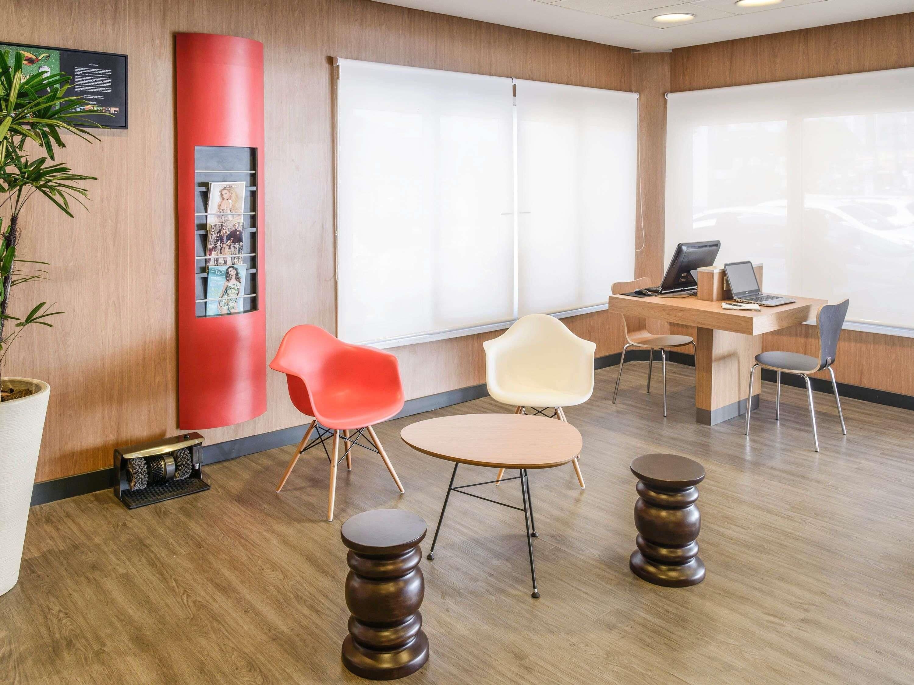 Un espacio de oficina moderno con piso de madera, un escritorio con computadora, dos sillas y un ventanal grande.