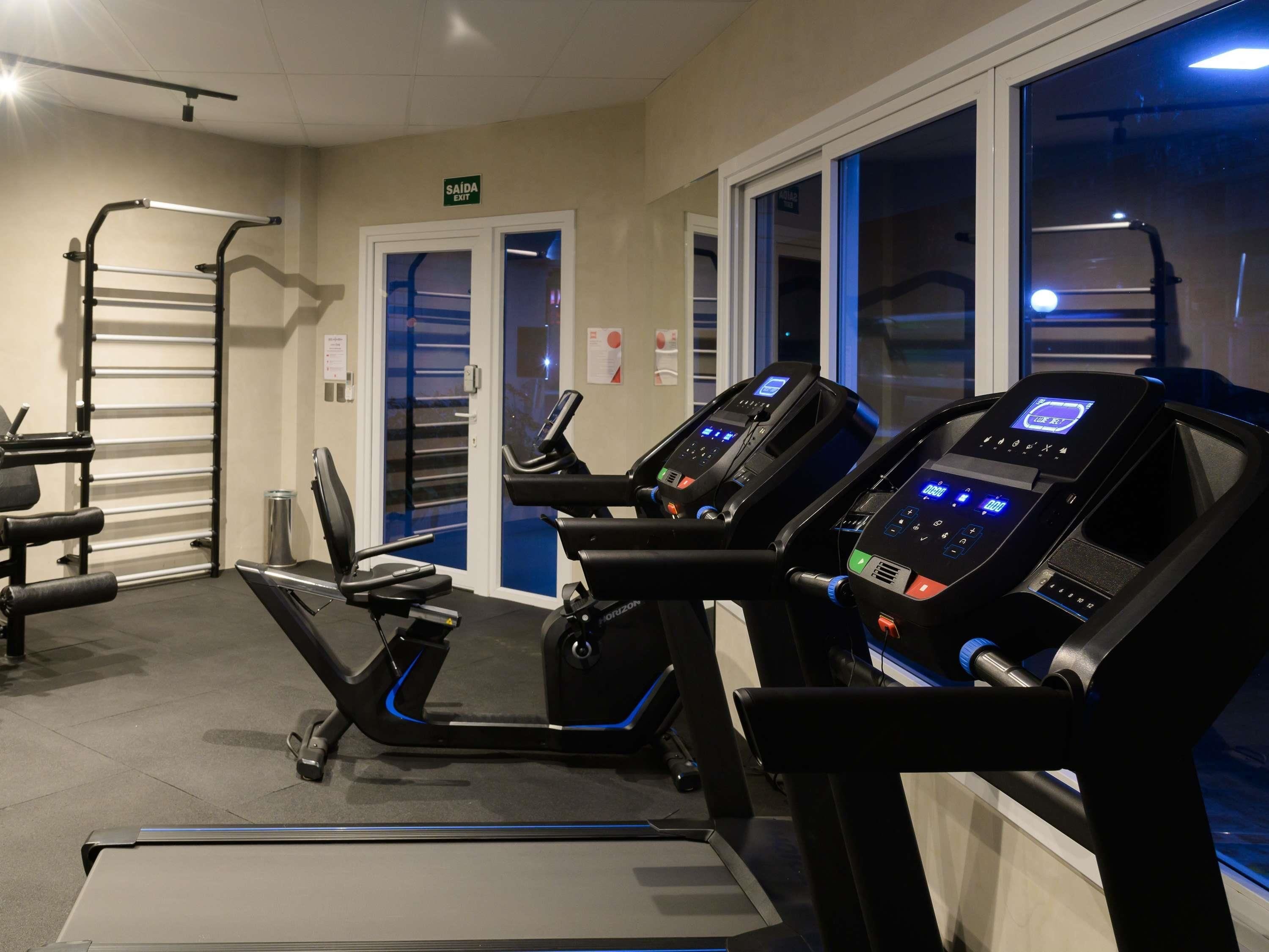 Un gimnasio con cintas de correr, una banca de pesas y una barra para dominadas.
