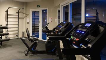 Un gimnasio con cintas de correr, una banca de pesas y una barra para dominadas.