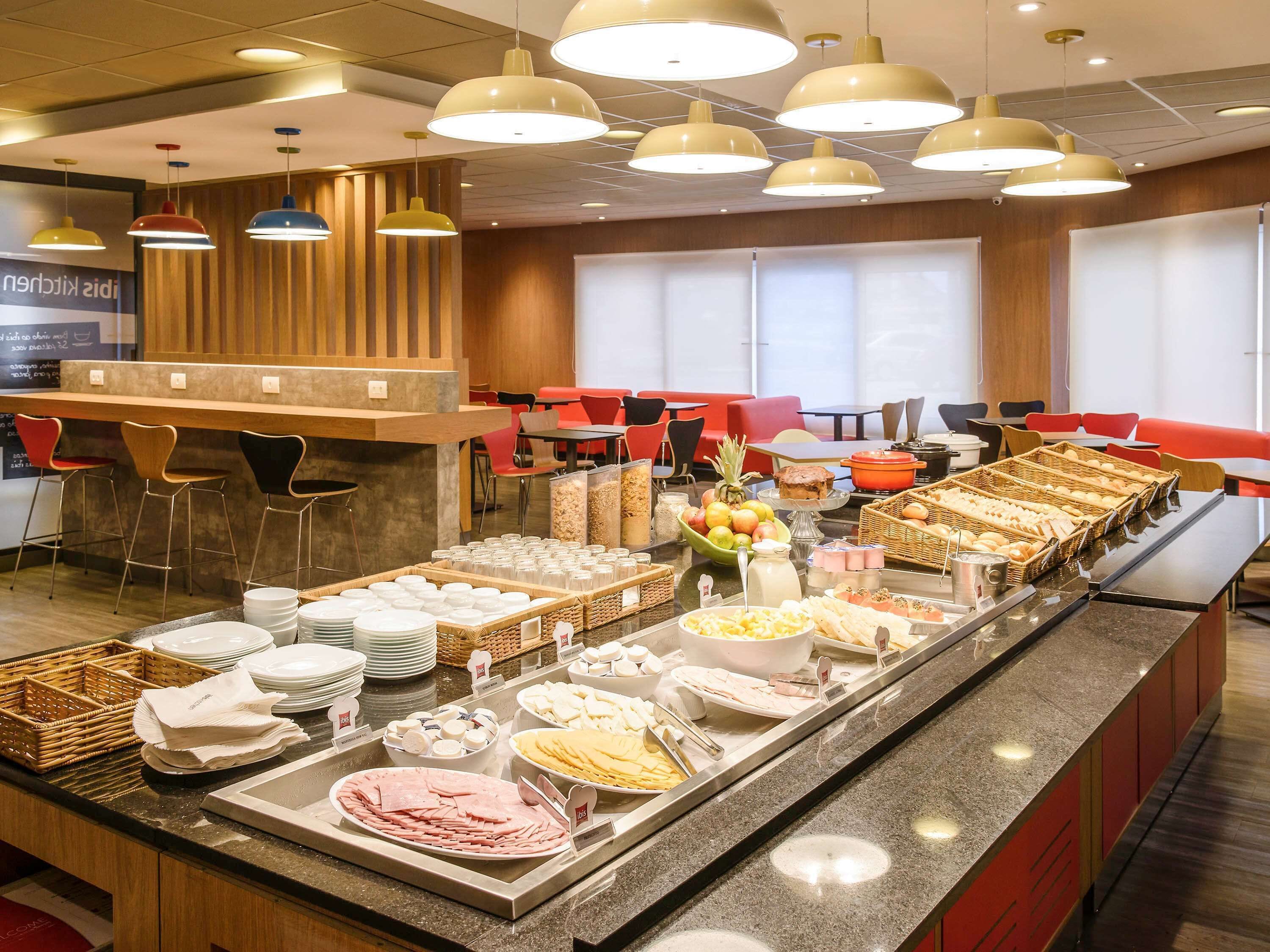 Un área de bufé con diferentes opciones de comida, un bar y mesas y sillas.