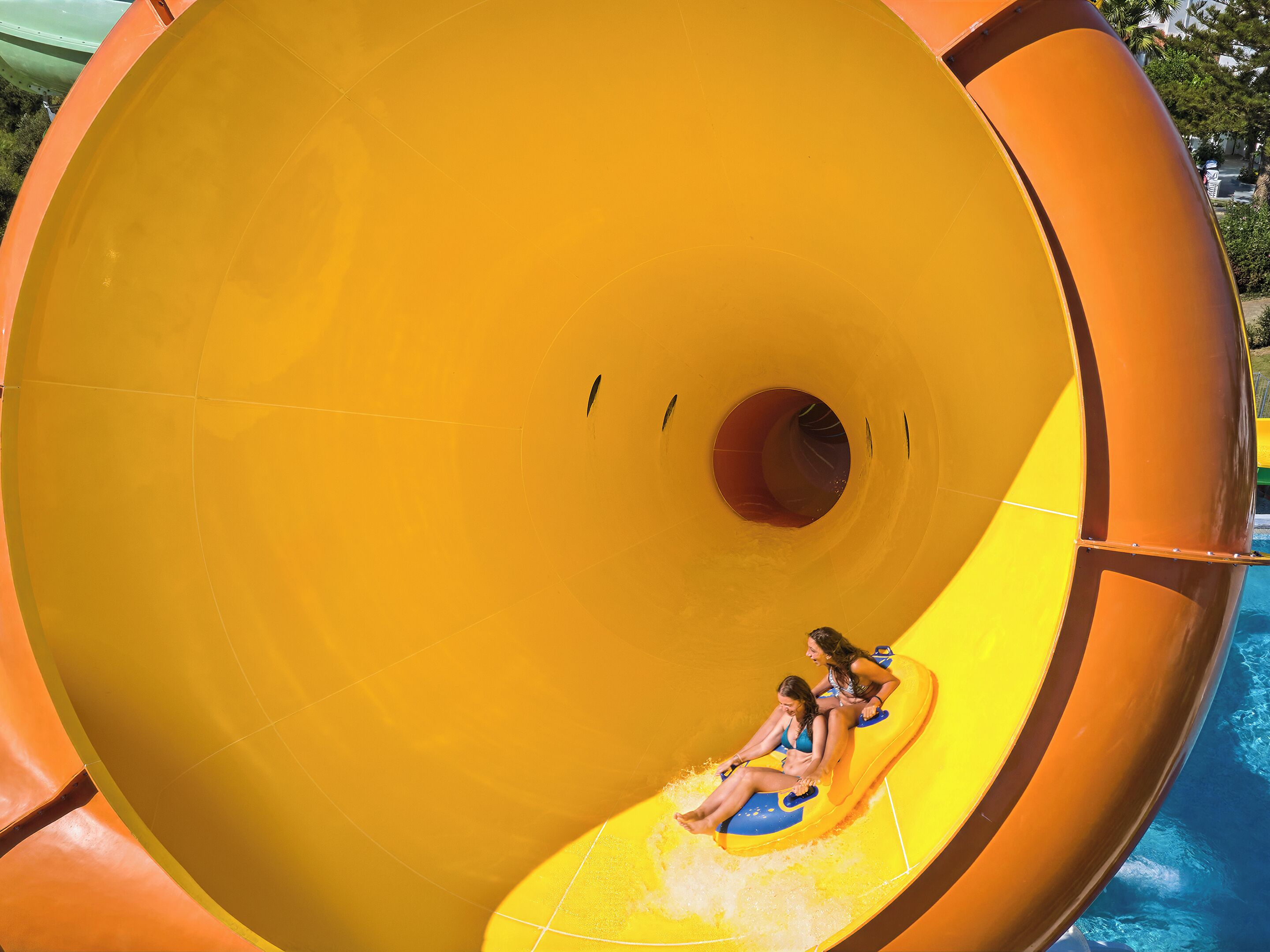 A large indoor water slide with a yellow interior and a pool at the bottom.