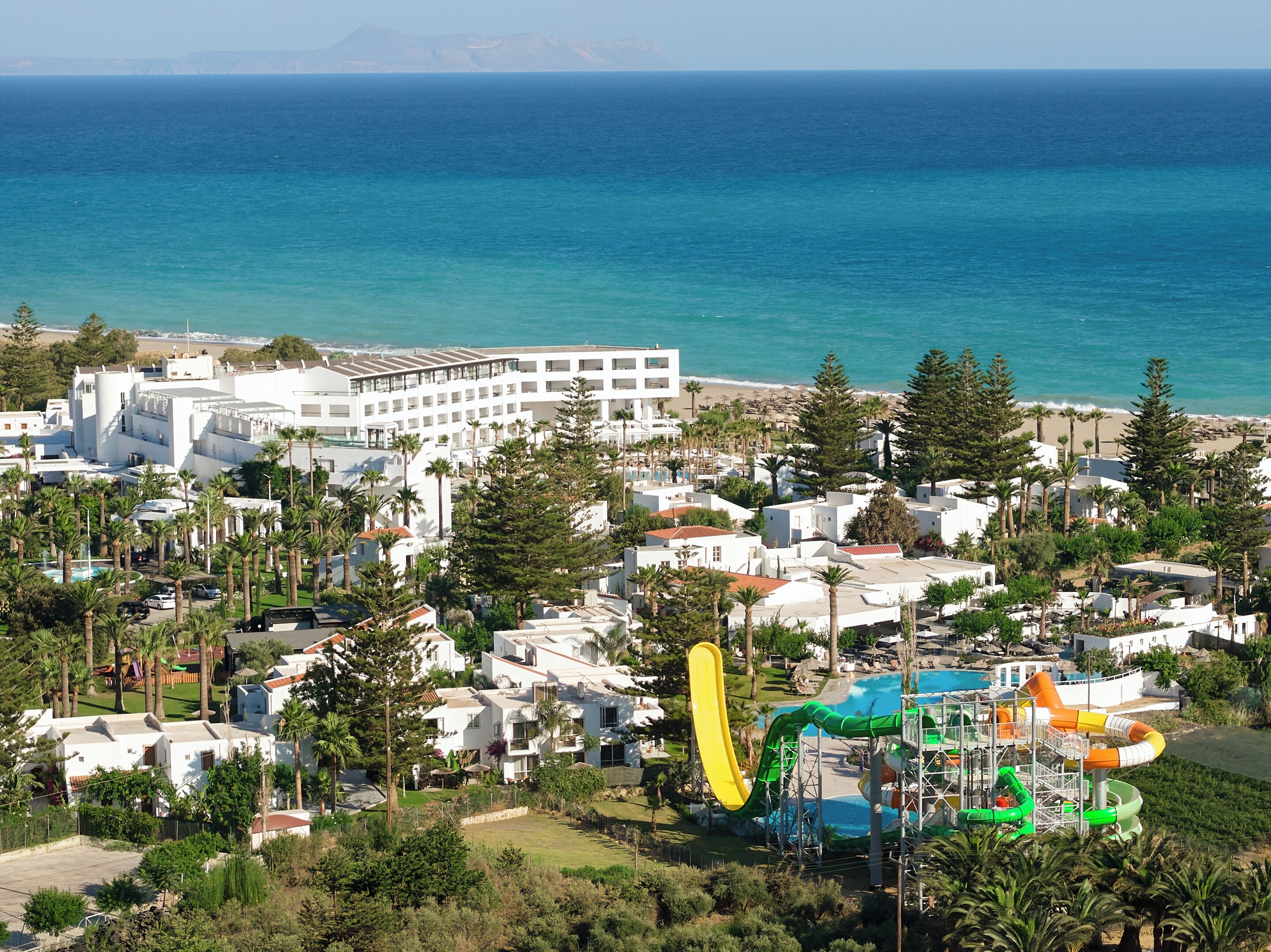 Un complejo turístico costero con parque acuático, edificios blancos y vistas al mar.