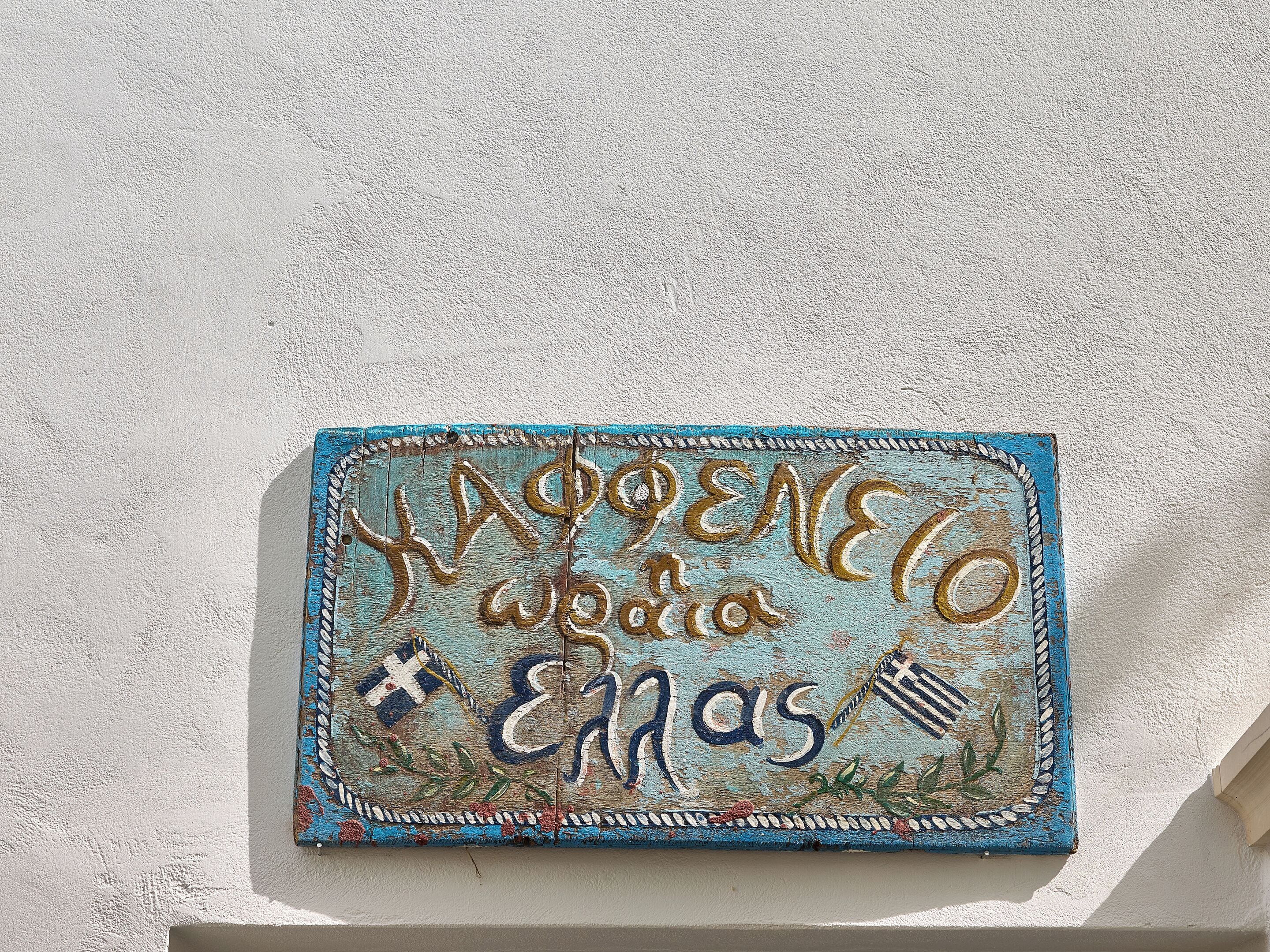 A textured wall with a decorative sign featuring text and symbols.