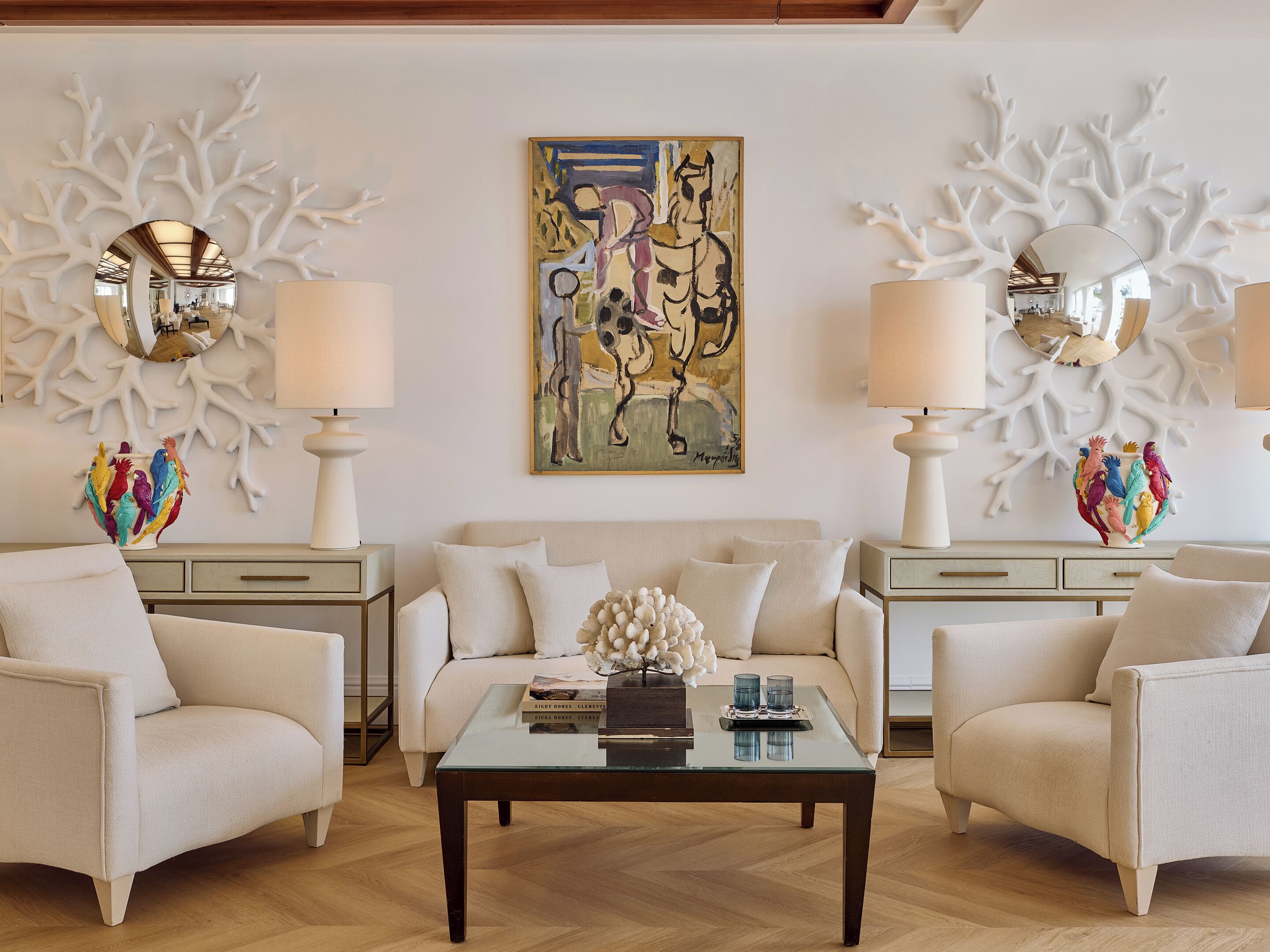 Sala de estar com sofá, duas poltronas, mesa de centro, arte decorativa nas paredes e duas luminárias.