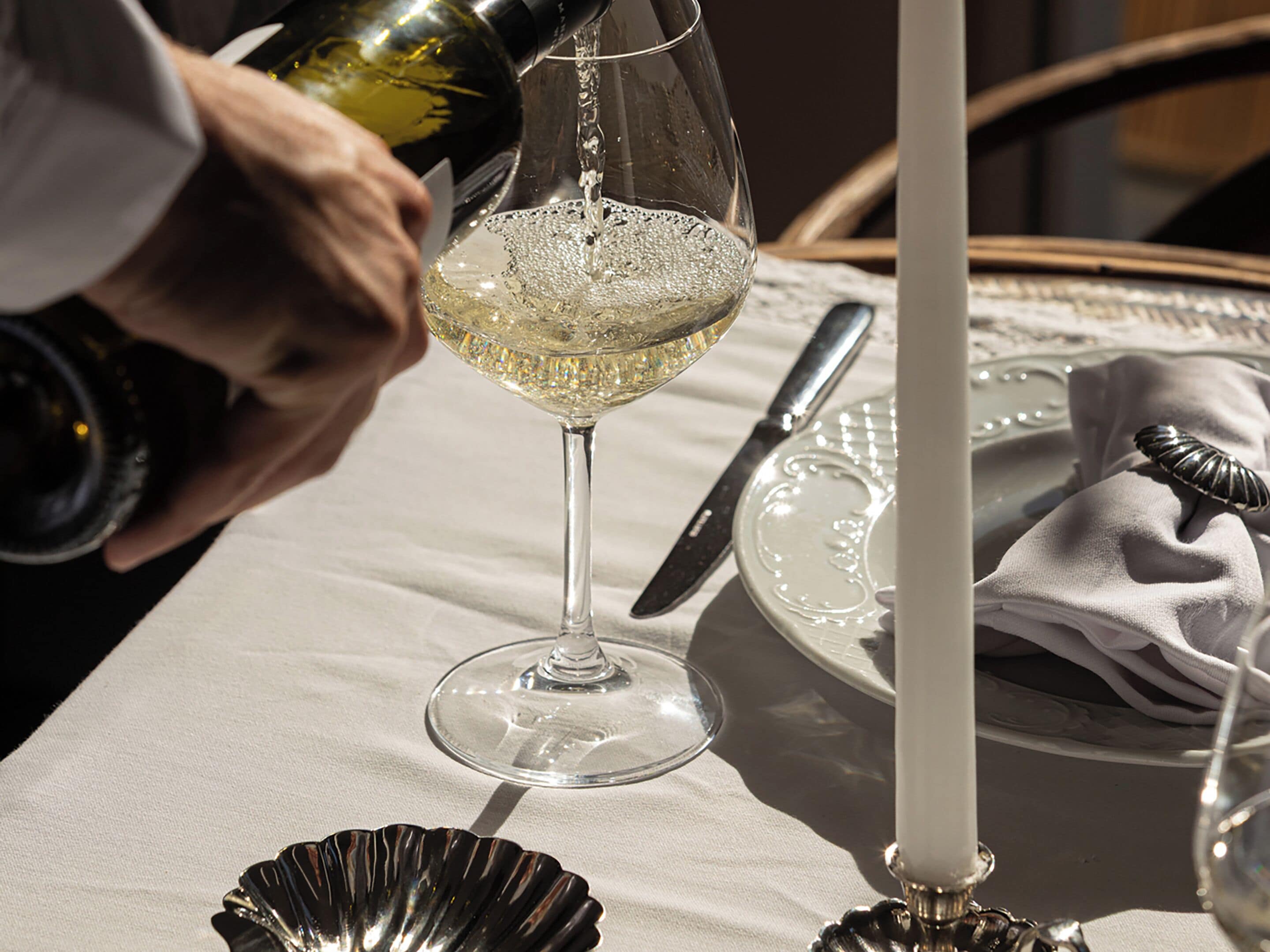 Una mesa dispuesta con una copa de vino, un cuchillo, un plato y una vela.