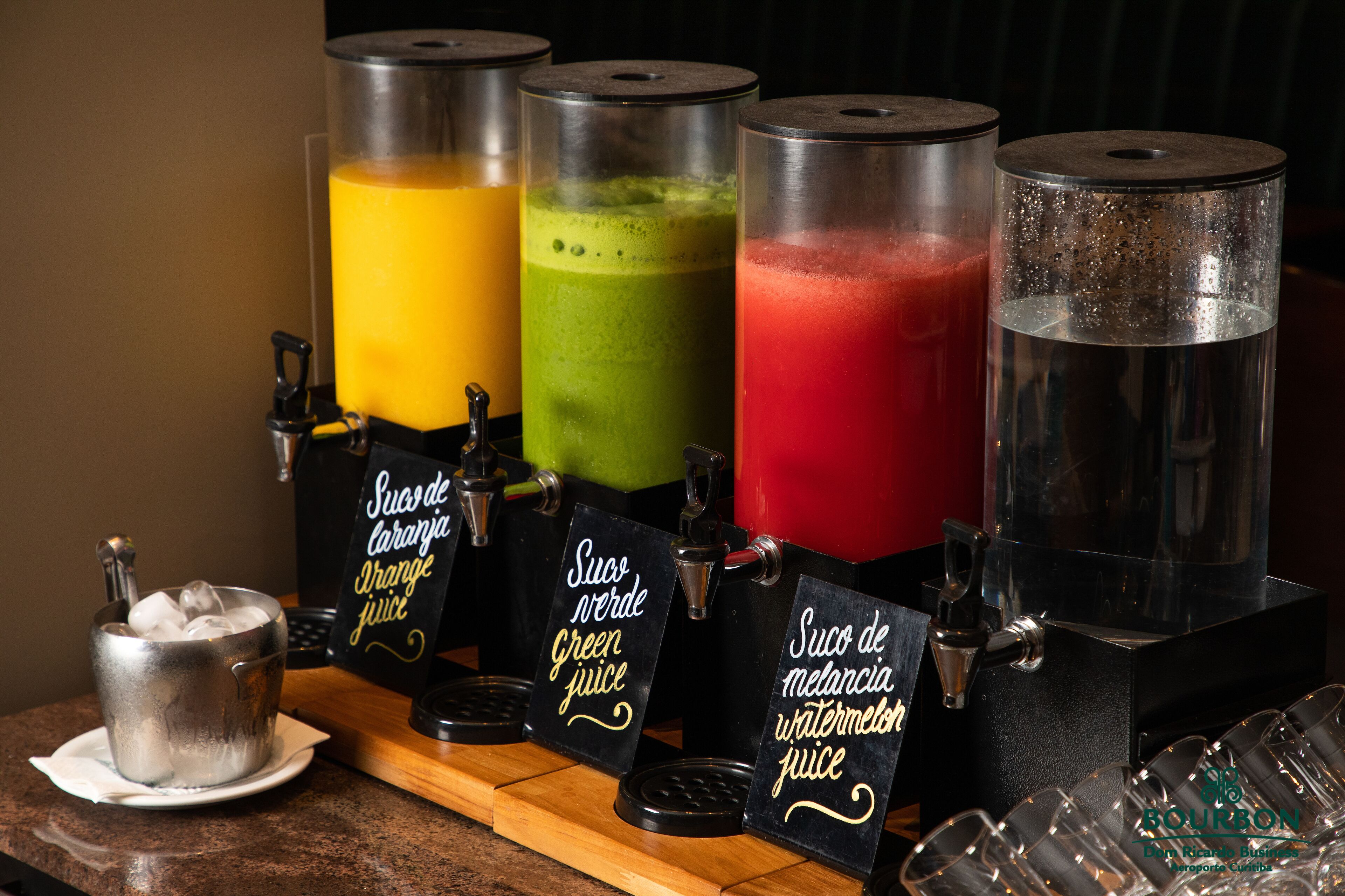 Bar de sucos com quatro dosadores identificados com diferentes tipos de suco.