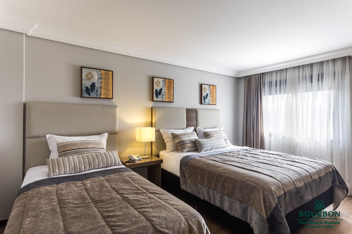 Une chambre d’hôtel avec deux lits, une table de chevet, une lampe et des œuvres d’art accrochées au mur.