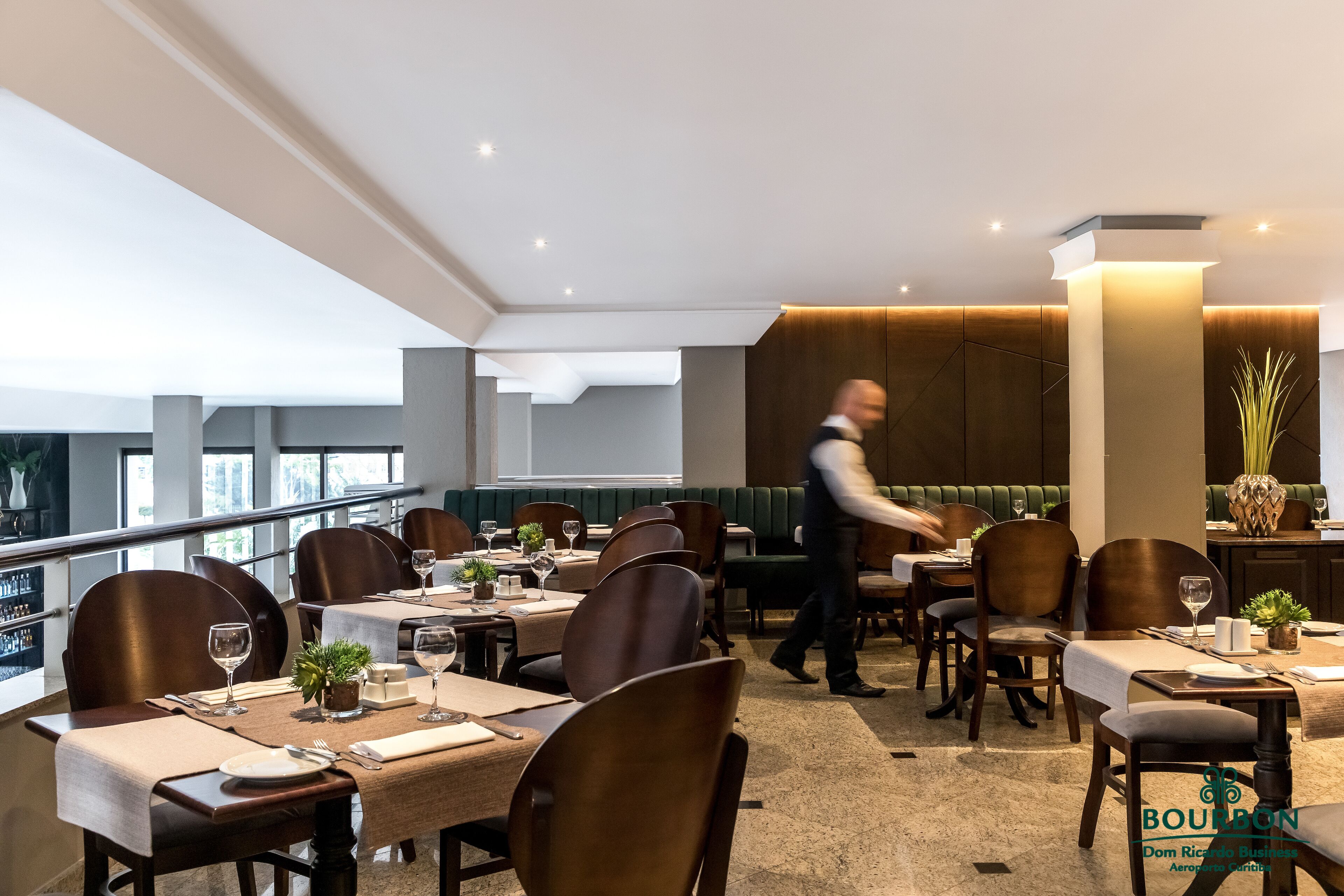 A modern restaurant with high tables, comfortable seating, and a view of the city.