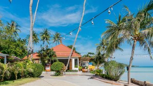 A house with a red roof, surrounded by palm trees and a clear blue sky.