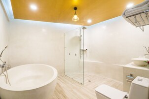 A modern bathroom with a freestanding bathtub, a glass-enclosed shower, and a white vanity with a sink and mirror.