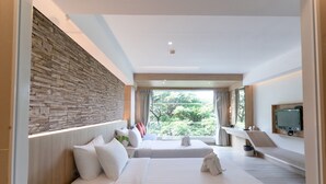 A modern hotel room with a stone accent wall, a large window with a view of greenery, a flat-screen TV, and a desk with a chair. - MATCHA SAMUI RESORT (Koh Samui)
