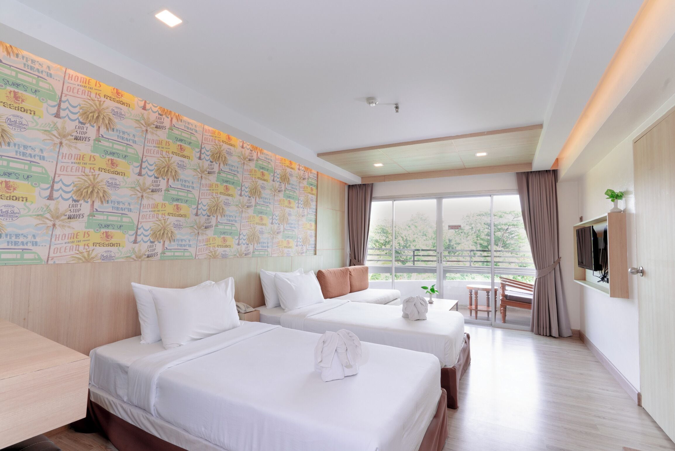 A hotel room with two beds, a large window, a TV, and a wall with a map design.