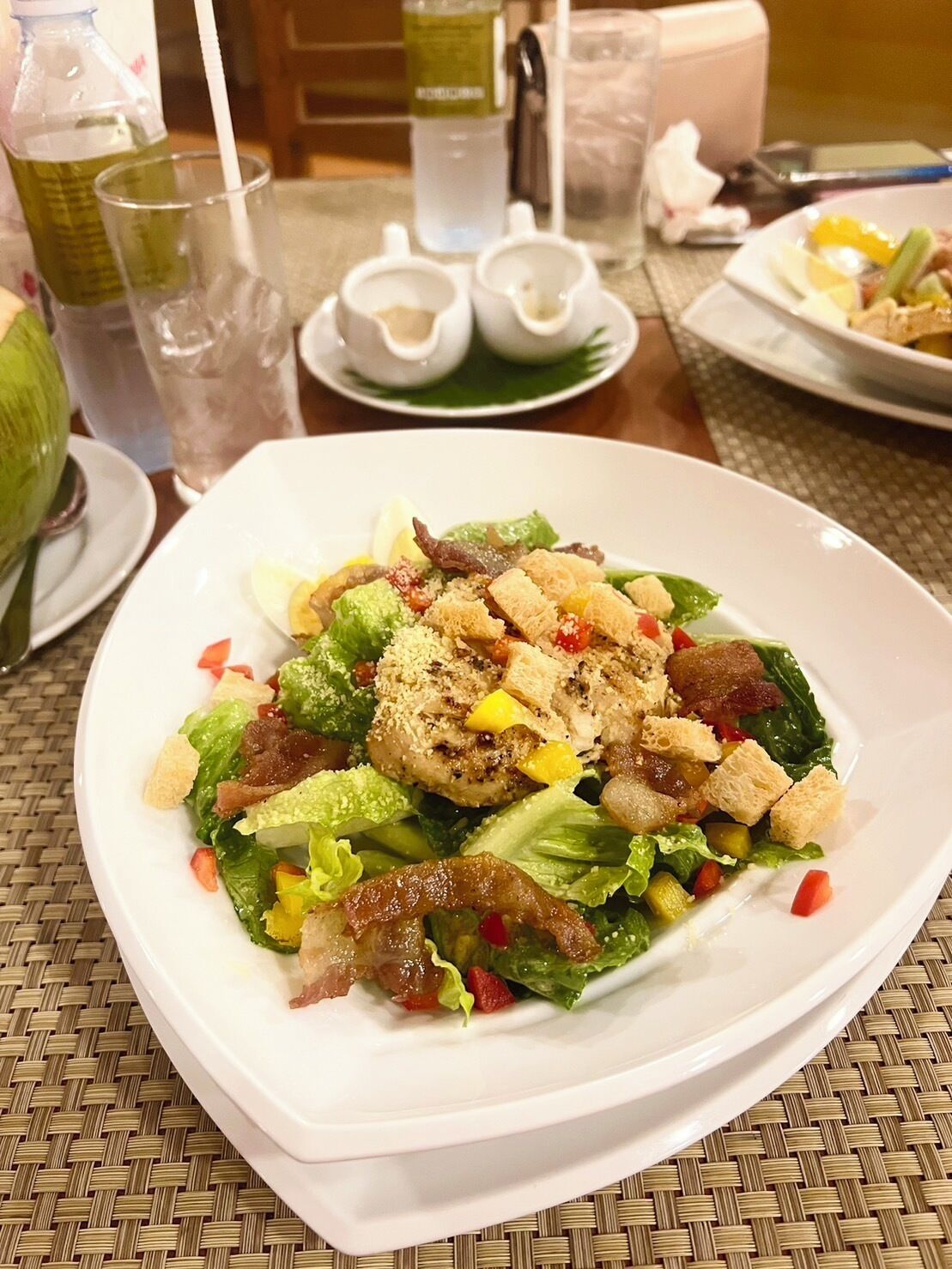 A white plate with a salad on a woven table mat.