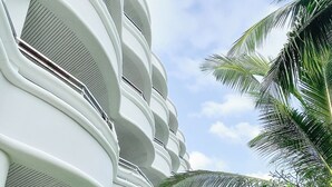 A modern hotel with multiple balconies, a well-maintained lawn, and palm trees. - MATCHA SAMUI RESORT (Koh Samui)