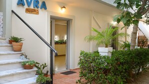 A staircase with potted plants leading to a door marked "AVRA." - Avra (Agios Vasileios)