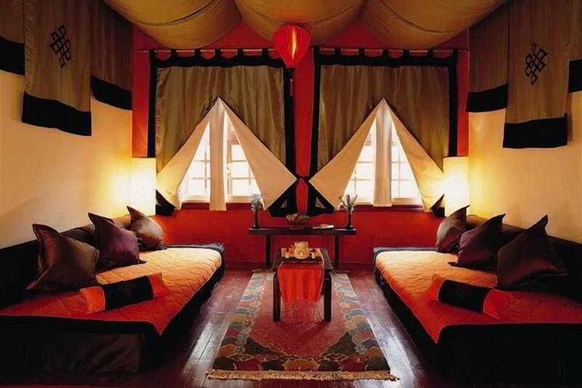 A room with two beds, a central table, and curtains.