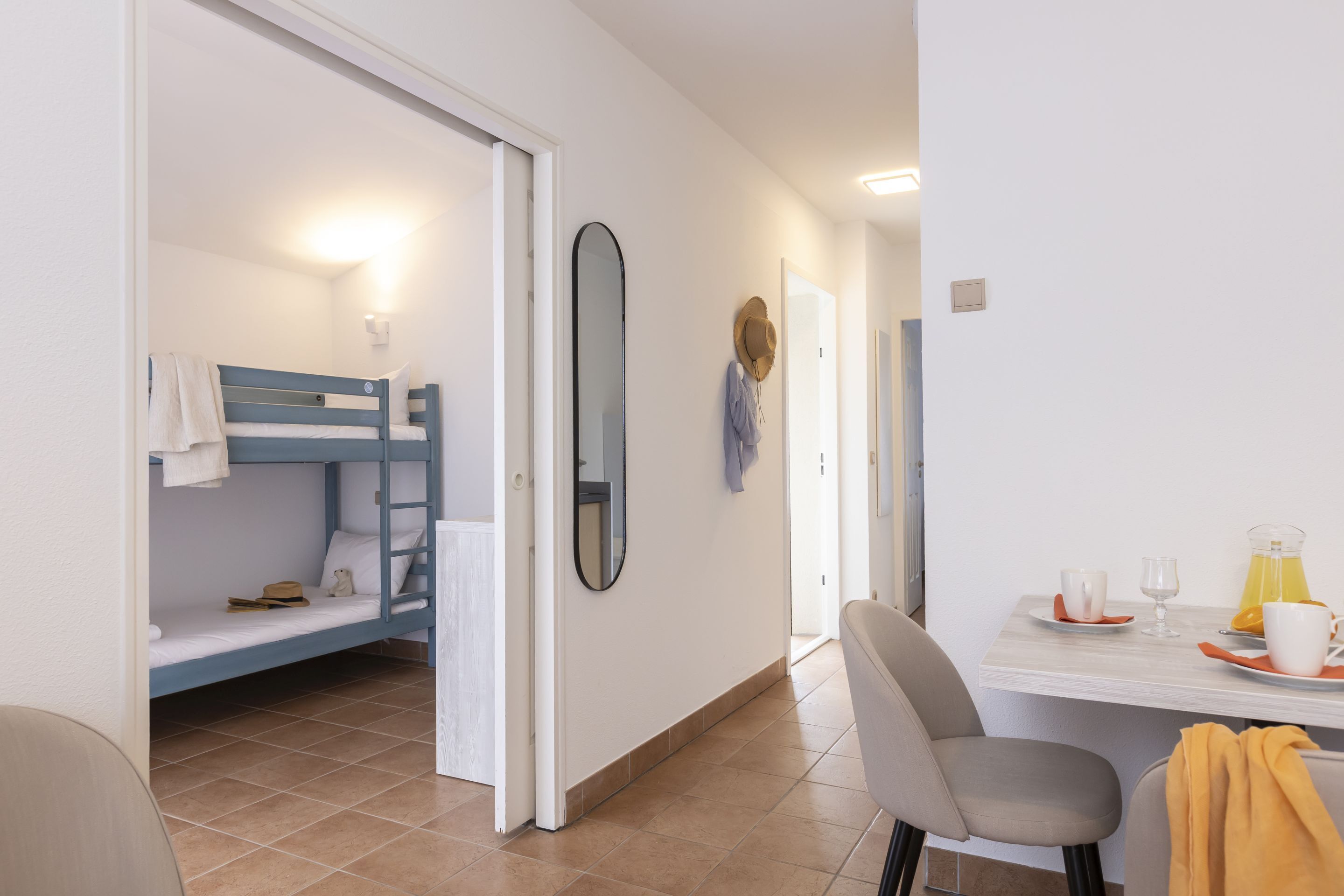 Ein Zimmer mit Etagenbett, Tisch mit Frühstücksangeboten und Spiegel an der Wand.