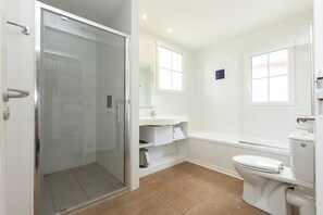 A modern bathroom with a glass shower enclosure, a white sink, a bathtub, and a toilet. - Résidence Odalys Domaine Les Greens du Bassin d'Arcachon (Gujan-Mestras)