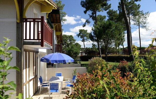 A hotel patio with outdoor seating and a blue umbrella.