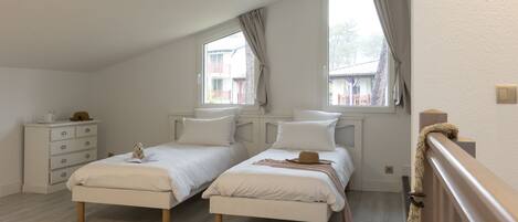 Une chambre avec deux lits, une commode et une fenêtre avec des rideaux.