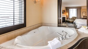 Un baño de hotel con una bañera grande, un espejo y una ventana con persianas.