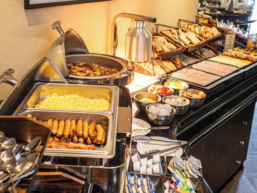 Un buffet con diverse opzioni di cibo, posate e un quadro appeso al muro.