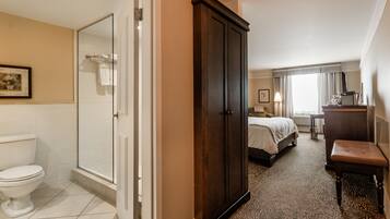 A hotel room with a shower, toilet, bed, and a large wardrobe.