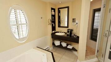 A bathroom with a bathtub, a sink with a mirror, and a shower area.