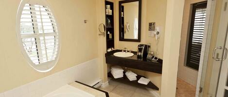 A bathroom with a bathtub, a sink with a mirror, and a shower area.