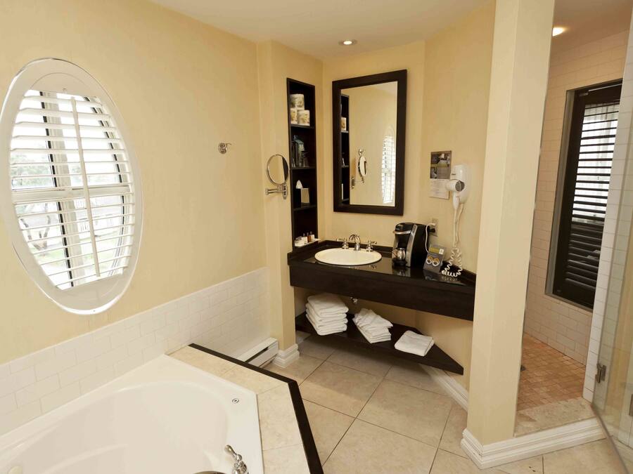 A bathroom with a bathtub, a sink with a mirror, and a shower area.