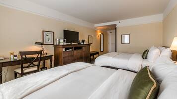 Een hotelkamer met twee bedden, een bureau, een stoel, een kast en een televisie.