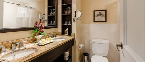 A bathroom with two sinks, a toilet, a shower curtain, a mirror, and a framed picture on the wall.