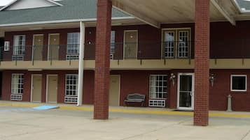 A two-story building with a flat roof, brick facade, and a covered entrance area with a bench.
