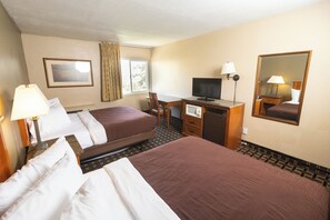 A hotel room with a large bed, a desk with a computer, a chair, and a television.