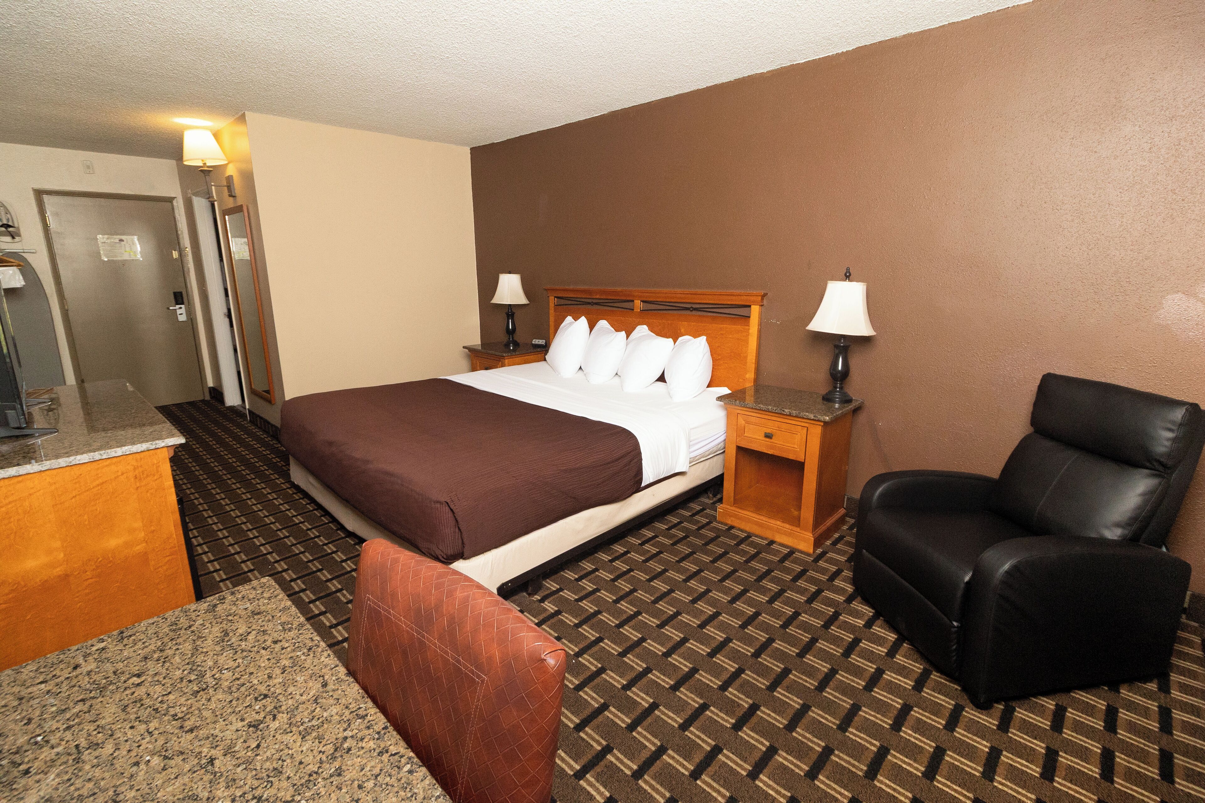 Une chambre d’hôtel avec un lit, un bureau, une chaise et une porte de salle de bain.