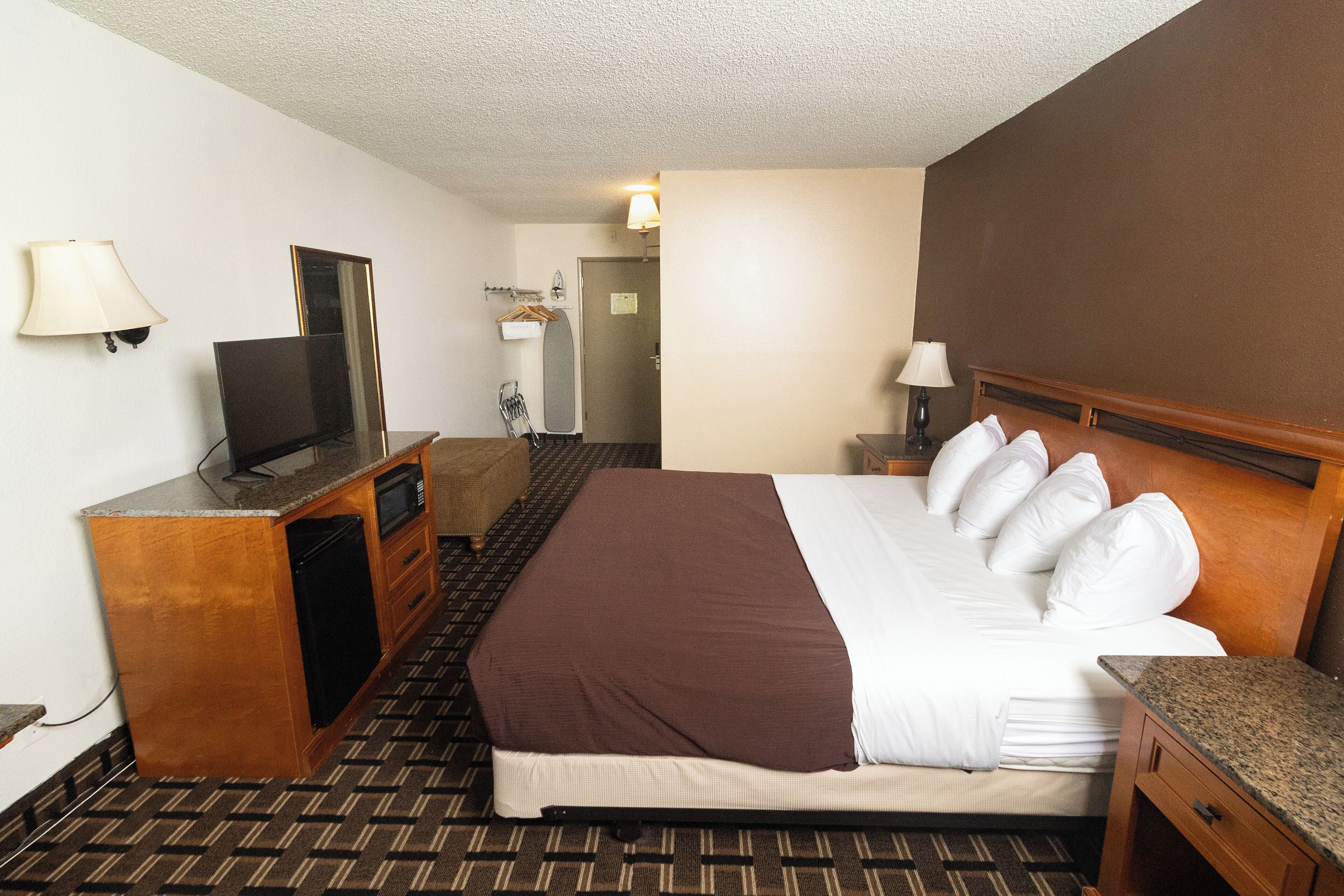 A hotel room with a bed, a television, a desk, and a mirror.